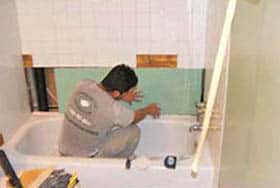 Ceramic bath tile being repaired around a bathtub demonstrates why the bathtub should be refinished last.